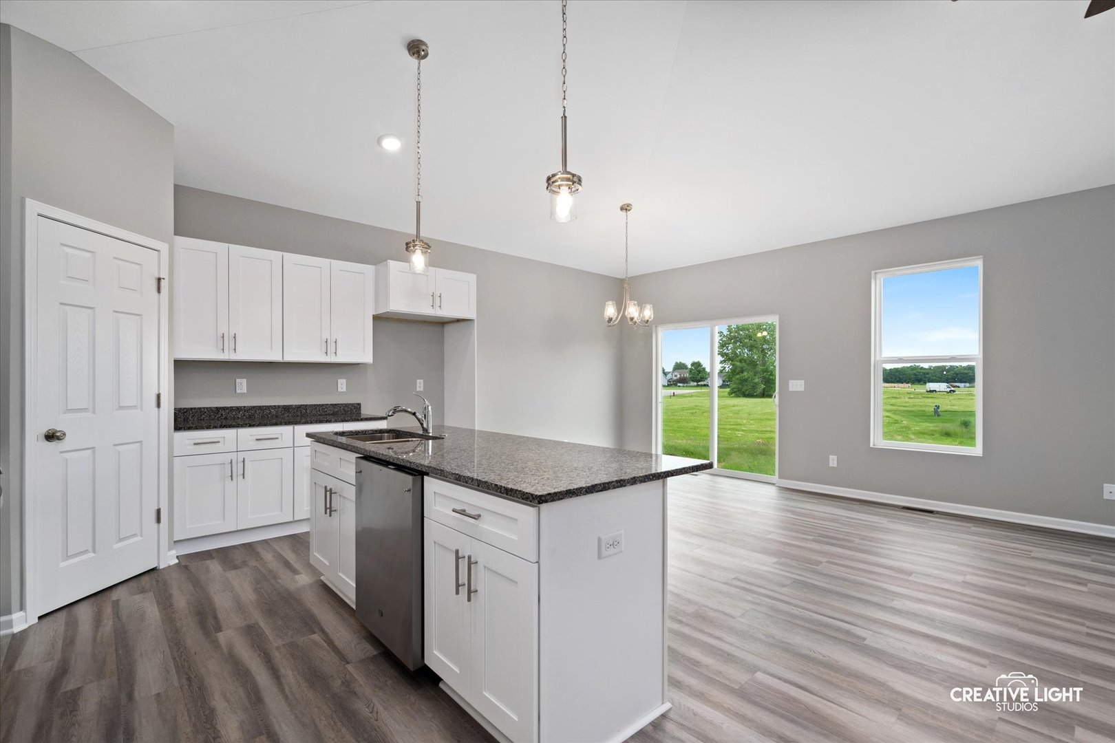 526 Hahn Drive Cortland, IL 60112 - Photo 2 of 20 a kitchen with granite countertop a stove a sink and white cabinets with wooden floor next to windows