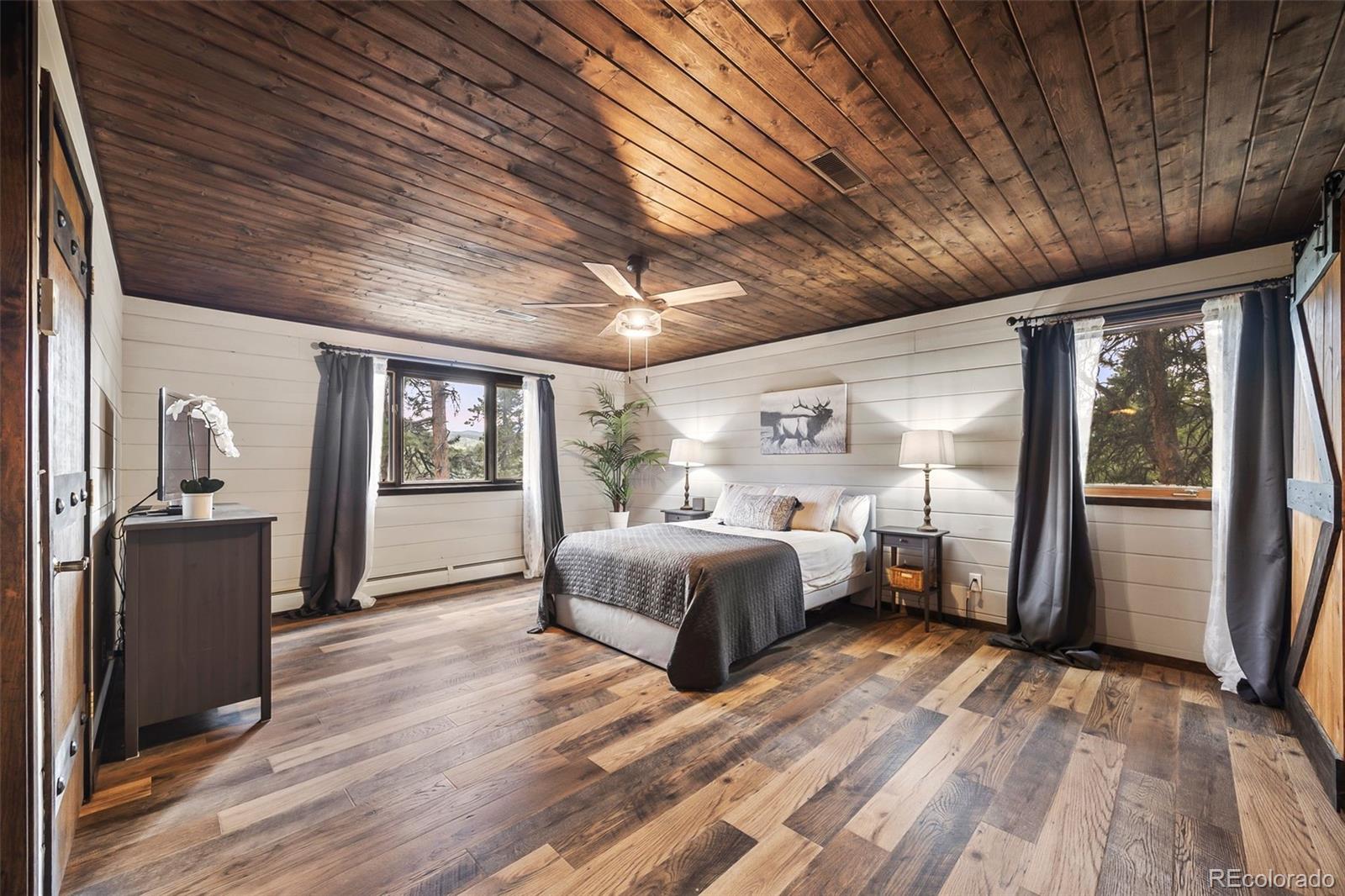 193 Mary Beth Road Evergreen, CO 80439 - Photo 17 of 46 a spacious bedroom with a bed and wooden floor