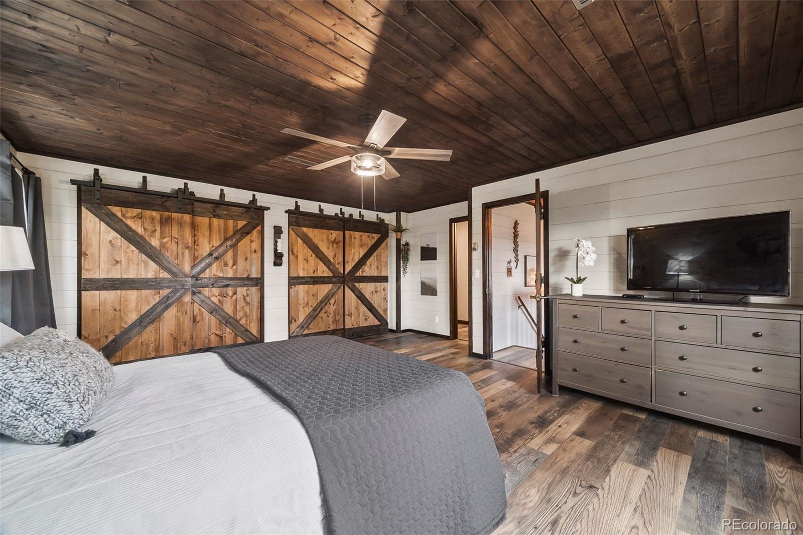 193 Mary Beth Road Evergreen, CO 80439 - Photo 19 of 46 a bedroom with a large bed and a flat tv screen on dresser