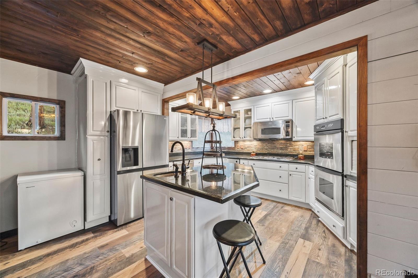 193 Mary Beth Road Evergreen, CO 80439 - Photo 6 of 46 a kitchen with stainless steel appliances granite countertop a refrigerator a sink dishwasher a stove and white countertops with wooden floor
