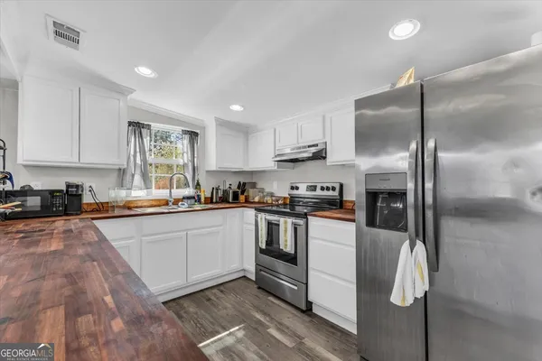 a kitchen with stainless steel appliances granite countertop a refrigerator a stove and a sink