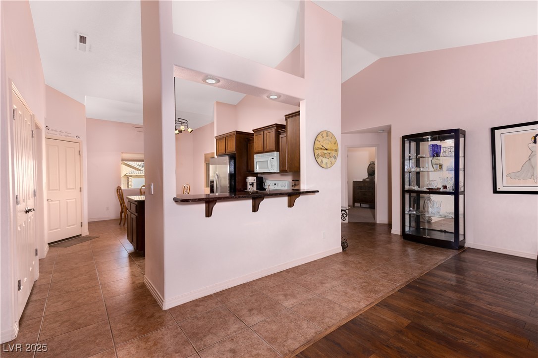 844 Sagedell Road Mesquite, NV 89027 - Photo 5 of 19 Kitchen with a breakfast bar, stainless steel fridge, white microwave, a peninsula, and dark tile patterned floors