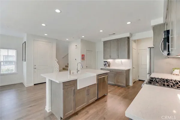 a large kitchen with stainless steel appliances a stove a sink dishwasher and a dining table with wooden floor