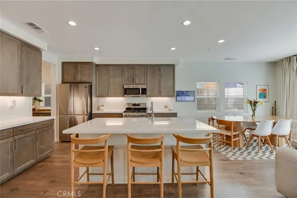 a large white kitchen with a sink and dishwasher a stove with wooden floor