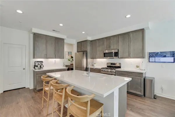 a kitchen with stainless steel appliances kitchen island granite countertop a dining table chairs and refrigerator