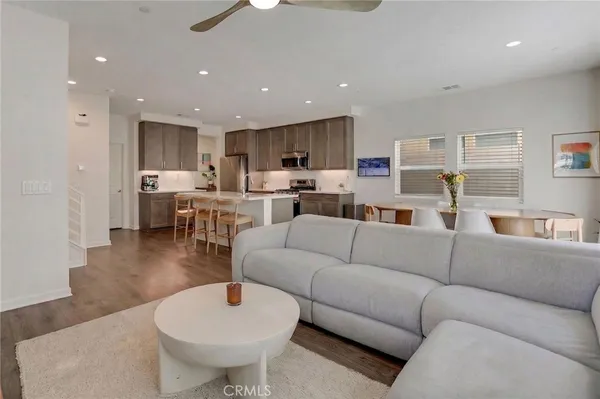 a living room with furniture and a dining table with wooden floor