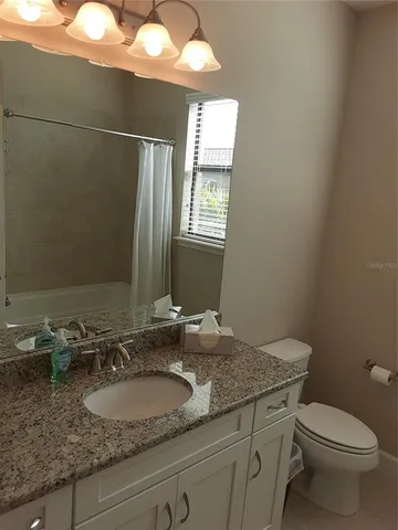 a bathroom with a granite countertop sink a toilet and mirror