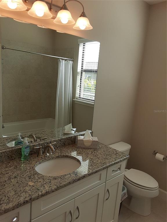 13605 Messina Loop, Unit 104 Bradenton, FL 34211 - Photo 23 of 38 a bathroom with a granite countertop sink a toilet and mirror