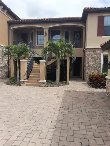 a view of a house with potted plants and a table and chairs