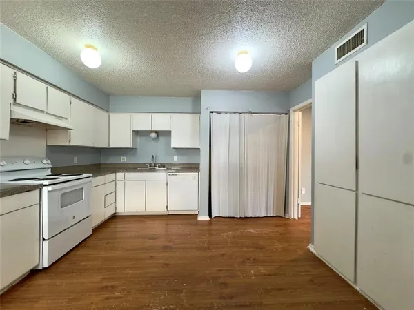a kitchen with granite countertop white cabinets and stainless steel appliances