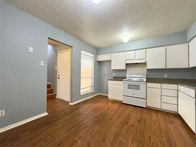 a kitchen with granite countertop white cabinets and white appliances