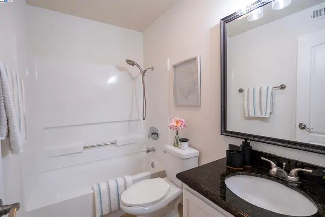 a bathroom with a granite countertop toilet sink and mirror