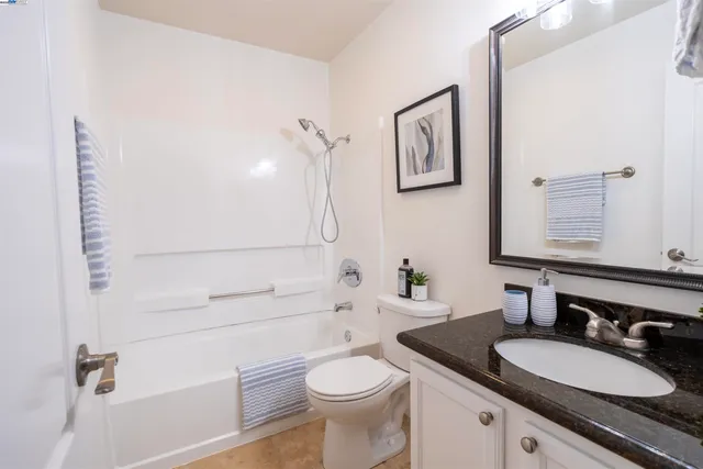 a bathroom with a granite countertop toilet sink and mirror