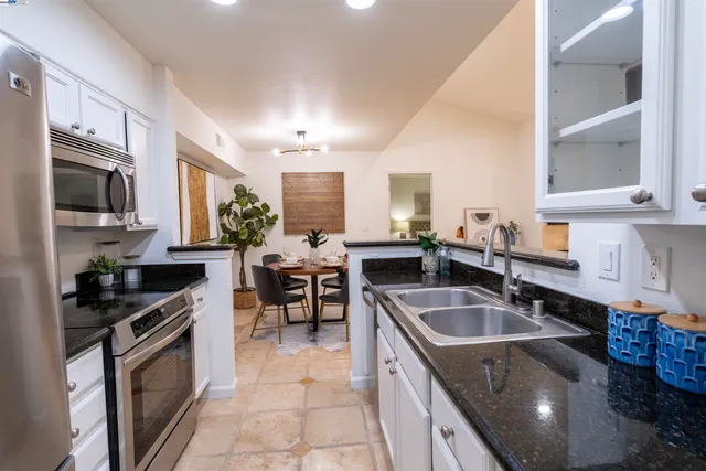 a kitchen with granite countertop a sink stainless steel appliances a counter space and cabinets