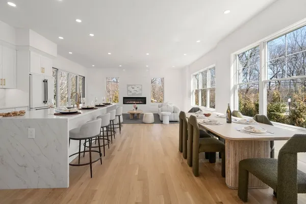 a open kitchen with stainless steel appliances granite countertop a stove a refrigerator a kitchen island a dining table and chairs with wooden floor