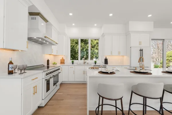 a kitchen with a stove a sink a kitchen island and chairs in it