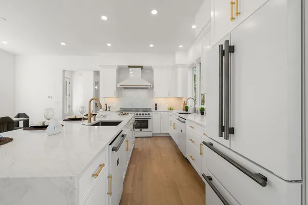 a large kitchen with stainless steel appliances a sink a counter top space a stove and cabinets