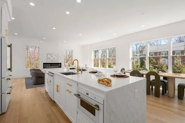 a view of a kitchen with kitchen island a stove a sink a refrigerator and a table