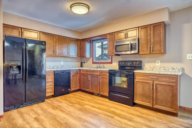 a kitchen with stainless steel appliances granite countertop a stove a sink dishwasher a refrigerator and cabinets with wooden floor