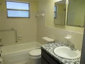 a bathroom with a granite countertop sink a toilet and a bathtub