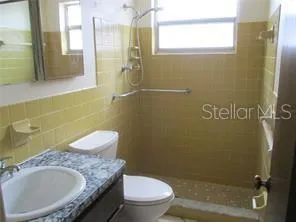 a bathroom with a granite countertop toilet a sink and mirror