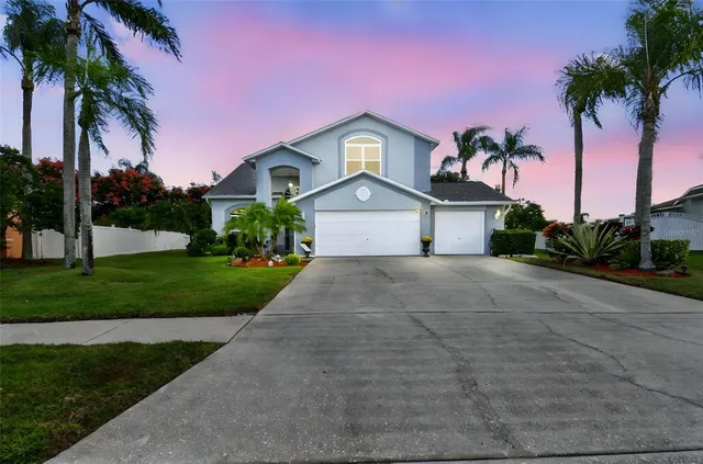 a front view of a house with a yard and palm trees