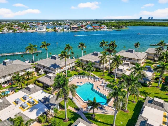 an aerial view of ocean and residential houses with outdoor space