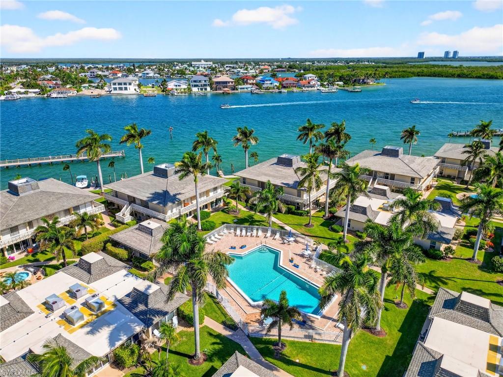 an aerial view of ocean and residential houses with outdoor space
