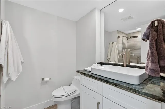 a spacious bathroom with a granite countertop sink a toilet a mirror and shower