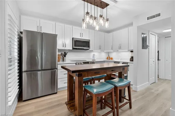 a kitchen with stainless steel appliances granite countertop a refrigerator a sink a stove a microwave and dining table