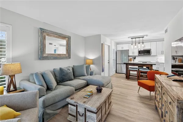 a living room with furniture kitchen view and a window