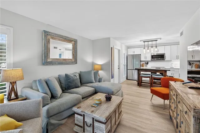 a living room with furniture kitchen view and a window