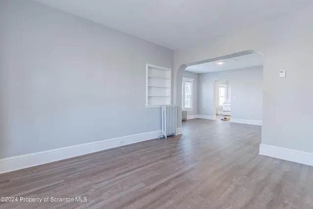 a view of an empty room with wooden floor and windows