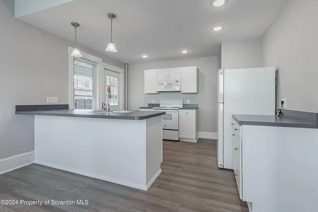 a kitchen with stainless steel appliances granite countertop a sink a stove a refrigerator and island with wooden floor