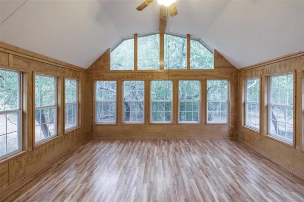 a view of empty room with wooden floor and fan