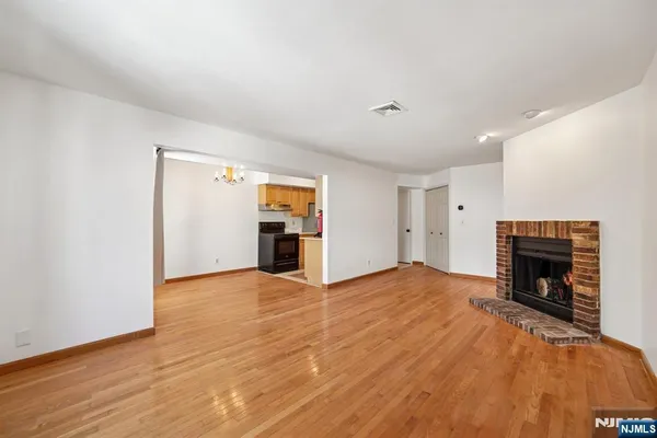 a view of empty room with wooden floor and fireplace