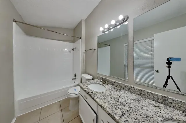 a bathroom with a granite countertop sink a toilet and shower