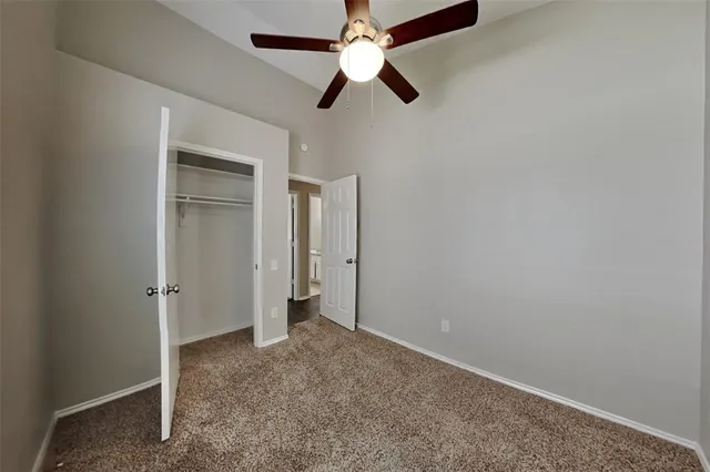 an empty room with closet and a chandelier fan