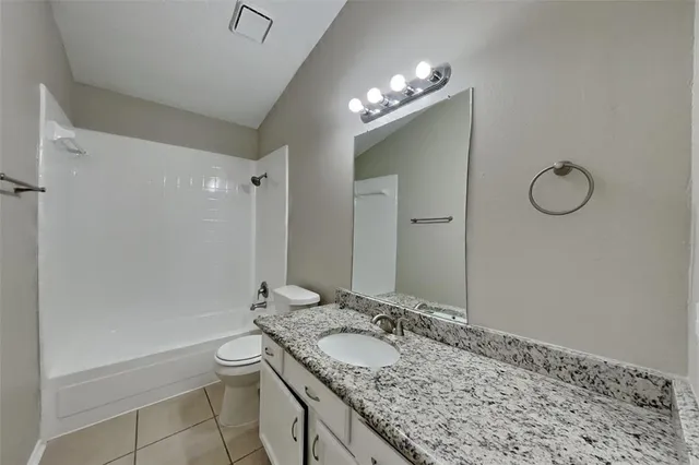 a bathroom with a granite countertop sink a toilet and a mirror