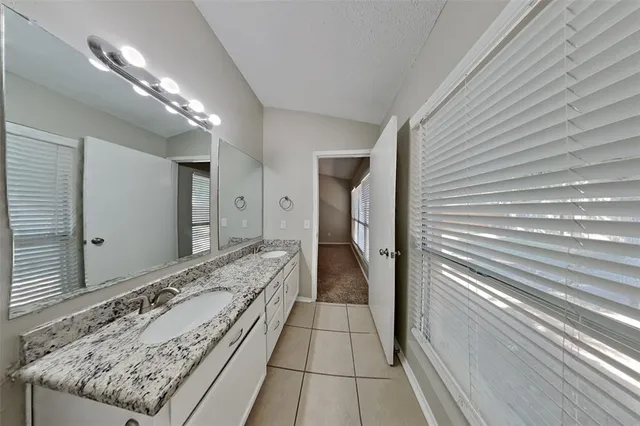 a en suite bathroom with a granite countertop sink and a mirror