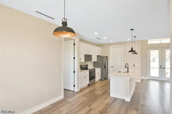 a room with stainless steel appliances a kitchen island hardwood floor and a sink
