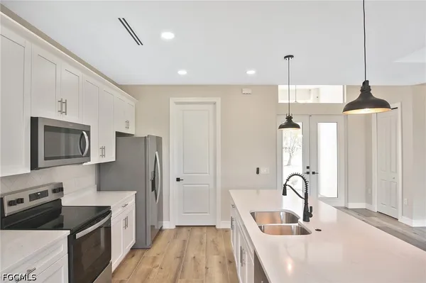 a kitchen with stainless steel appliances granite countertop a sink a stove a refrigerator cabinets and chairs