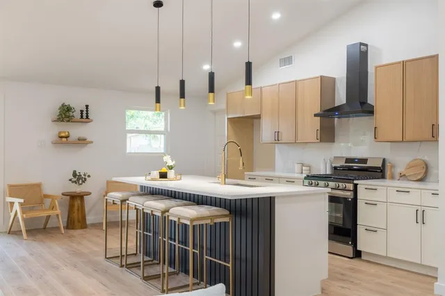 a kitchen with stainless steel appliances a stove a sink a dining table and chairs