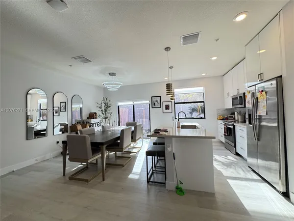 a living room with stainless steel appliances furniture a dining table and kitchen view
