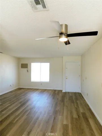 an empty room with wooden floor fan and windows