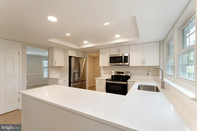 a large white kitchen with stainless steel appliances granite countertop lots of counter top space and a refrigerator
