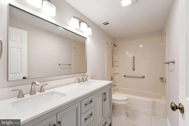 a bathroom with a granite countertop sink a toilet a shower and a mirror