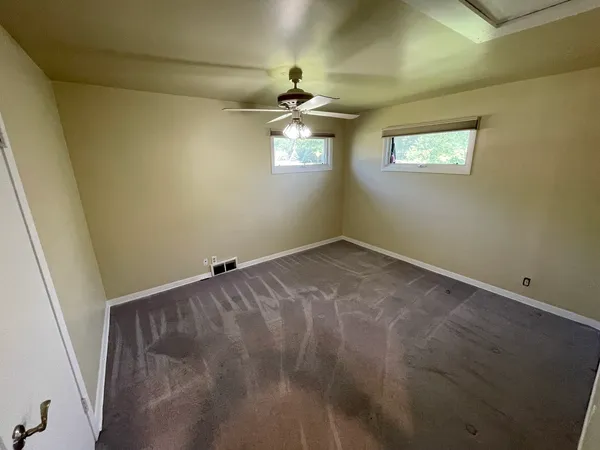 an empty room with windows and chandelier fan