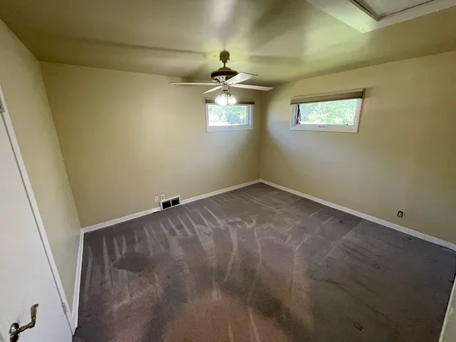 an empty room with windows and chandelier fan
