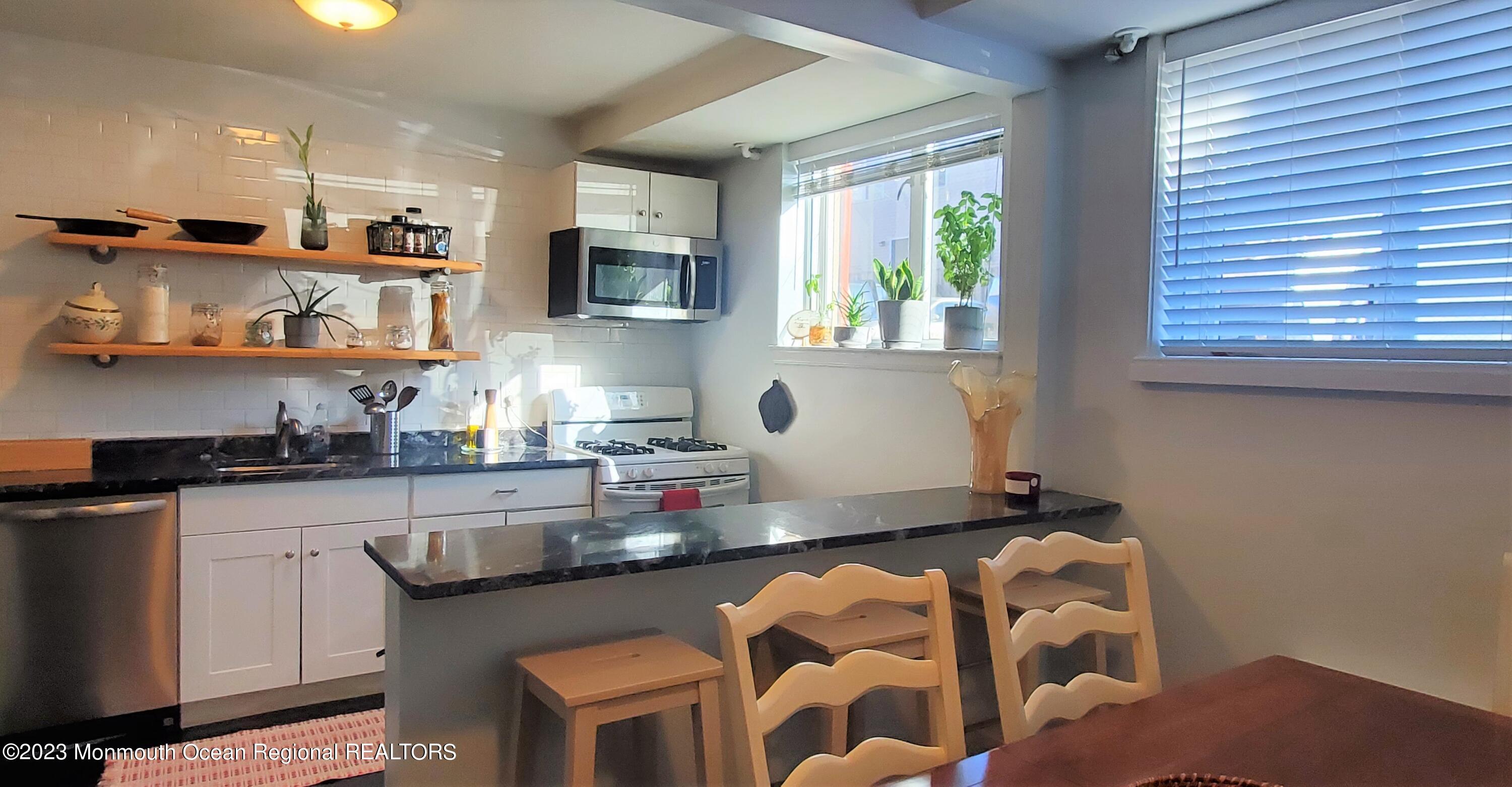 293 Spring Street, Unit 16A Red Bank, NJ 07701 - Photo 5 of 15 a kitchen with stainless steel appliances granite countertop a sink a stove a microwave cabinets and a dining table